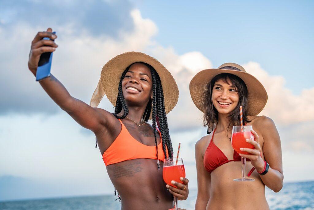 Diverse girlfriends taking selfie during summer holidays on beach